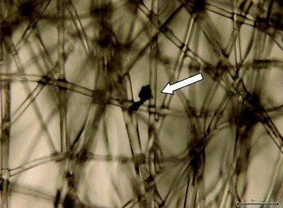 Microscopy photograph of felt from a CR cassette in use at the time of the Fukushima disaster. Suspended particulate matter (arrow; approximately 30-40 µm in diameter), which included cesium-134 and cesium-137 radioactivity, can be seen.