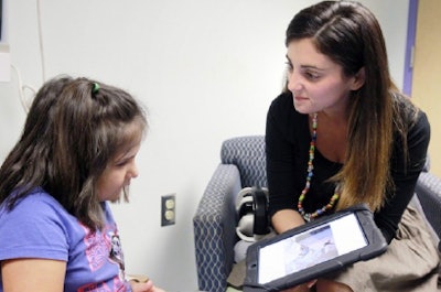 Vanderbilt Children's Hospital child life specialist Sarah Beth Gray explains to a young patient what will happen during her sedation-free MRI exam. Image courtesy of Dr. Ashish Parikh.