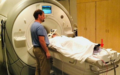 A study participant undergoes an fMRI scan while heat stimulus is applied to his leg (red arrow). Image courtesy of UC San Diego Health.