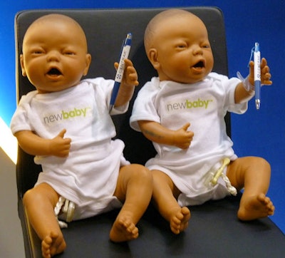 Two baby dolls holding pens