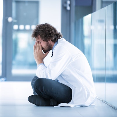 Doctor sitting on the floor with his head in his hands