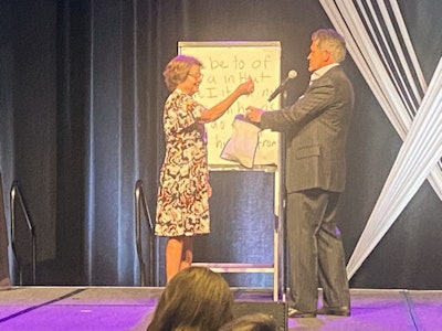 Mentalist Craig Karges has a volunteer pick a random piece of newspaper out of a bag for one of his demonstrations at the 2023 AHRA annual meeting. Through intuition, he correctly guessed the word that the volunteer pointed to on the piece of paper.