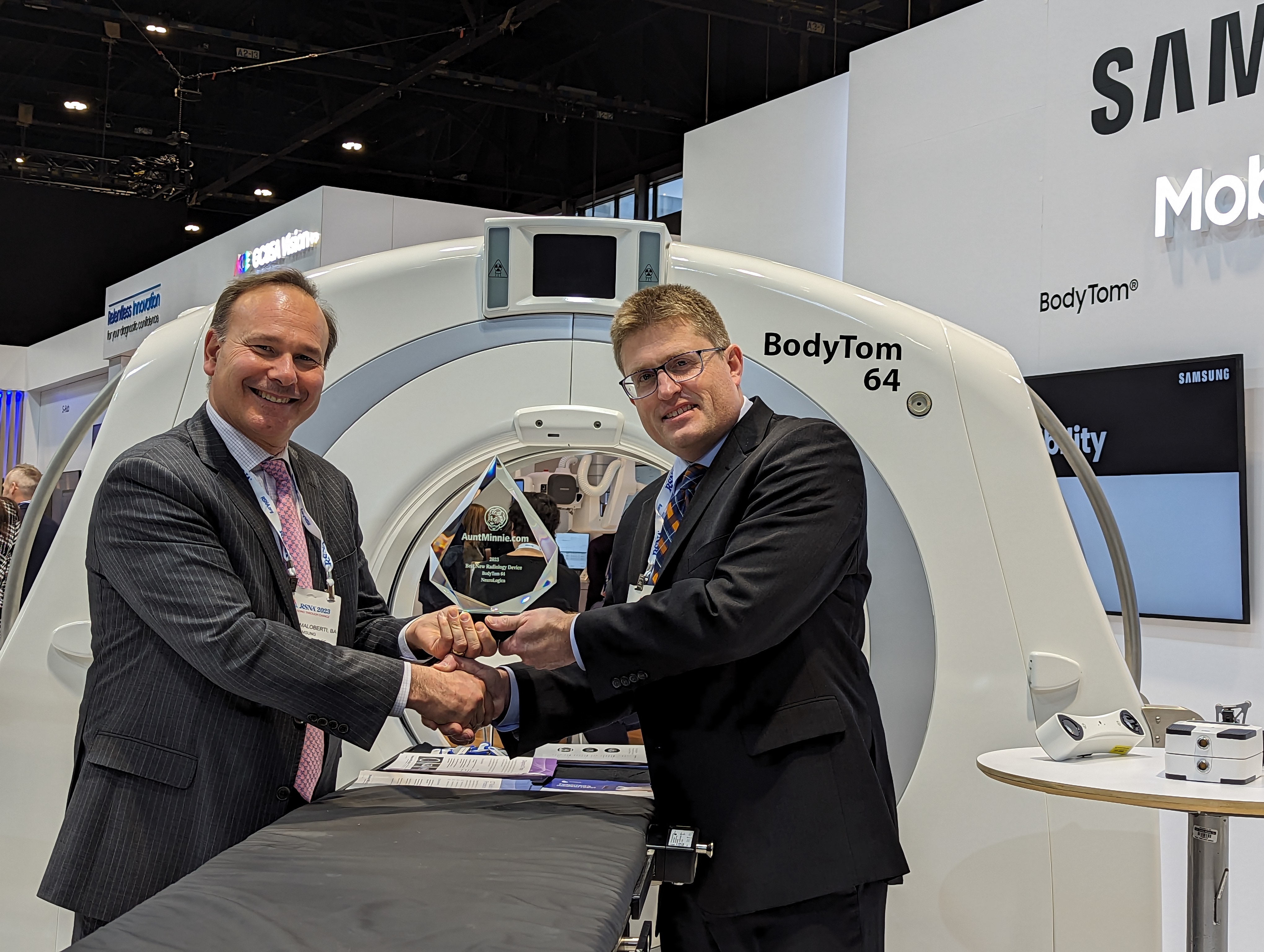Renaud Maloberti, vice president and head of mobile CT business at NeuroLogica, receives the 2023 Minnie for Best New Radiology Device from AuntMinnie.com Editor-in-Chief Erik Ridley. NeuroLogica was awarded the Minnie for its BodyTom 64 point-of-care mobile CT scanner.
