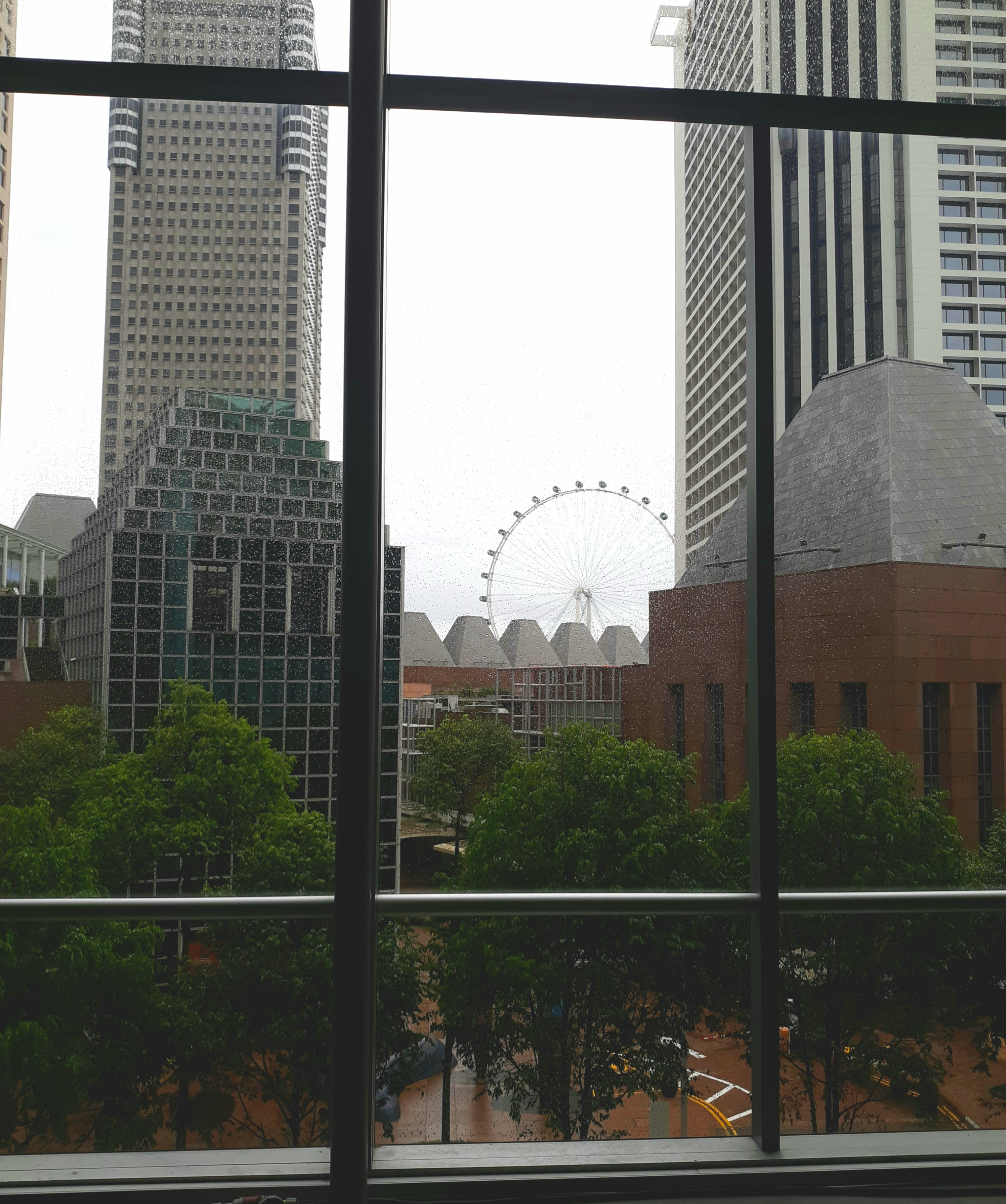 Singapore Flyer Ferris wheel through the conference center windows on a rainy morning