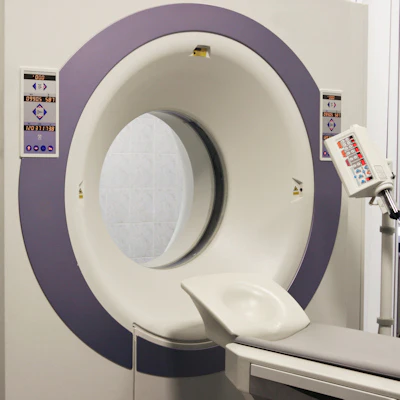 Purple and white medical CT or MRI scanner with open gantry and patient table in clinical facility