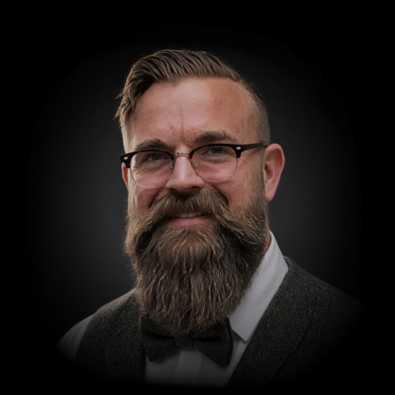 Professional portrait of bearded man wearing glasses and formal attire with bow tie
