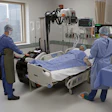 Medical team attending to patient in hospital room with diagnostic imaging equipment and monitoring systems