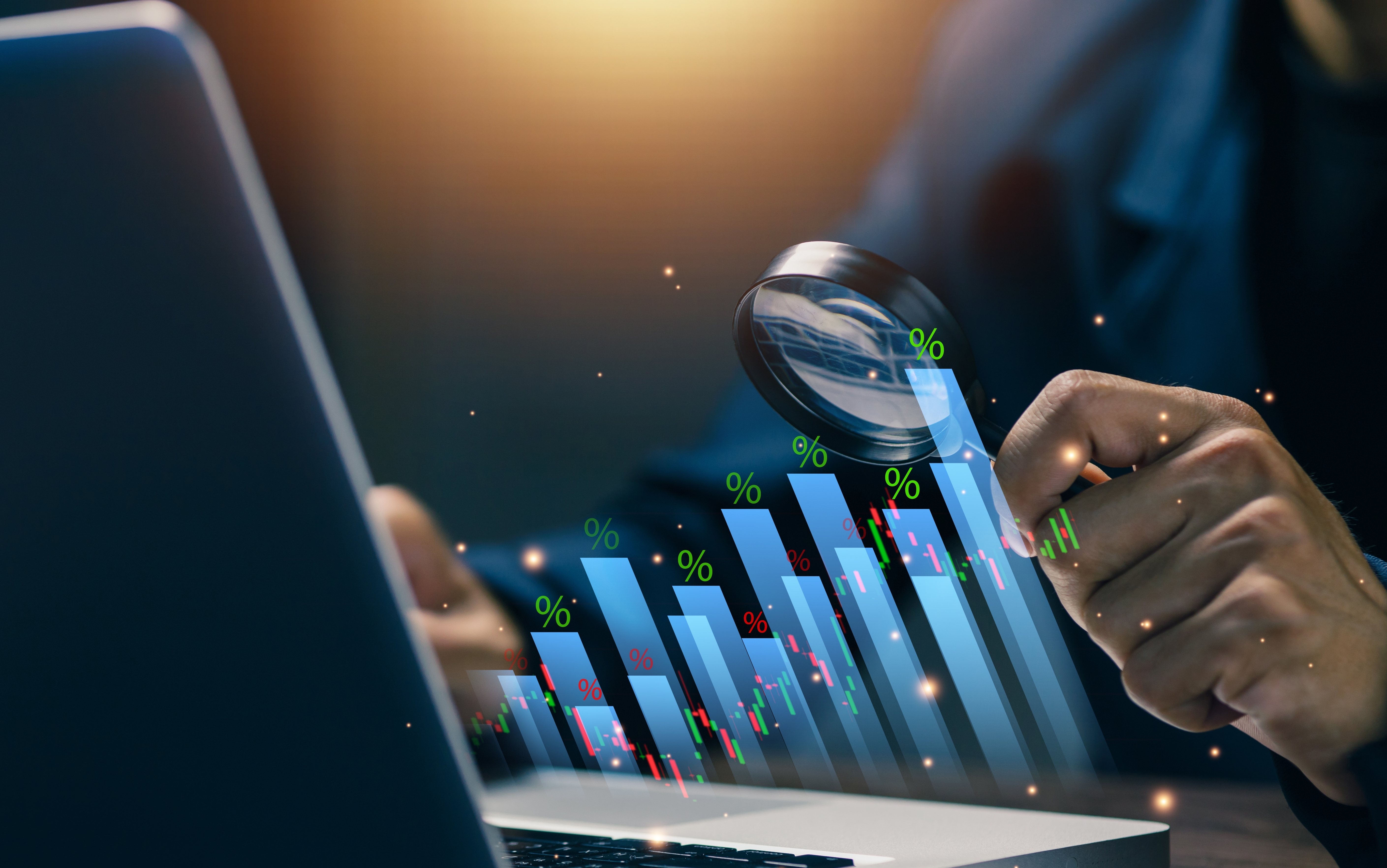 Business analyst examining financial data charts and percentages through magnifying glass on laptop screen