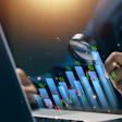Business analyst examining financial data charts and percentages through magnifying glass on laptop screen