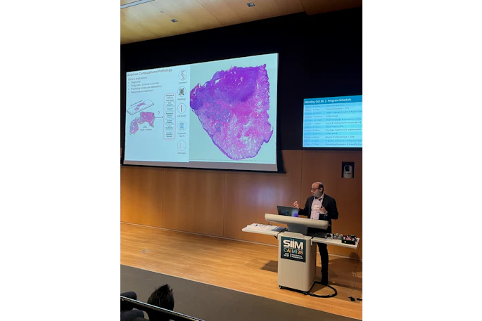 Medical researcher presenting computational pathology findings at SIIM CAIRM26 conference with tissue analysis visualization