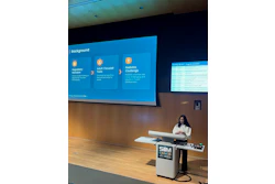 Woman presenting at SIM CAIM26 conference podium with blue program schedule displayed on projection screen