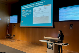 Female presenter delivering conference talk on AI and ICH outcomes at SIM event with projection screens