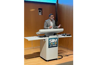 Professional speaker at podium with SIIM CAIMI26 conference logo during AI research awards presentation