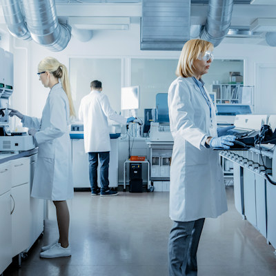 Scientists and technicians in white coats working in a modern laboratory with equipment and instruments.
