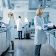 Scientists and technicians in white coats working in a modern laboratory with equipment and instruments.