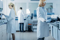 Scientists and technicians in white coats working in a modern laboratory with equipment and instruments.