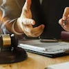 Two professionals reviewing legal documents at a desk with a gavel during a business consultation