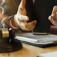 Two professionals reviewing legal documents at a desk with a gavel during a business consultation