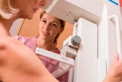Person smiling while looking in bathroom mirror with towel