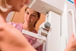 Person smiling while looking in bathroom mirror with towel