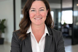 Professional woman in dark blazer and white blouse smiling in modern office setting