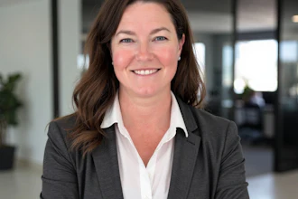 Professional woman in dark blazer and white blouse smiling in modern office setting