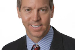 Professional headshot of a man in dark blazer and striped blue shirt with red tie