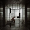 Dimly lit prison cell with barred doors and figure inside, conveying confinement and isolation
