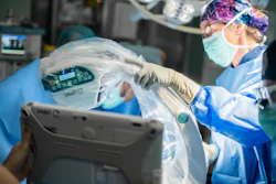 Surgeon in sterile protective gear inspecting a SMART C medical device during surgical procedure