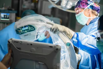 Surgeon in sterile protective gear inspecting a SMART C medical device during surgical procedure