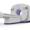 GE HealthCare CT scanner with gray housing, purple accent ring, and sliding patient table