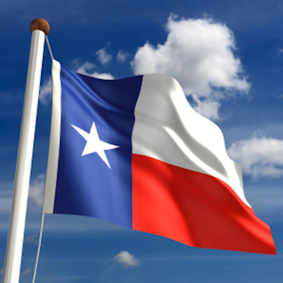 Texas state flag waving on a flagpole against a bright blue sky with white clouds
