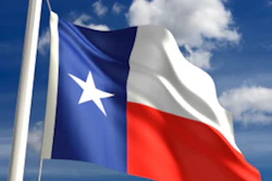 Texas state flag waving on a flagpole against a bright blue sky with white clouds