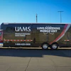 UAMS lung screening mobile unit parked at outdoor venue with Ferris wheel visible in background
