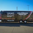 UAMS lung screening mobile unit parked at outdoor venue with Ferris wheel visible in background
