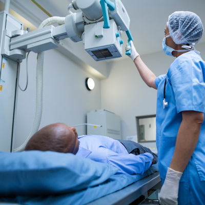 Healthcare provider adjusting medical imaging equipment over patient during diagnostic procedure